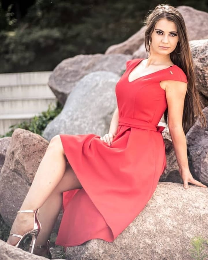 dziewczyna w czerwonej sukni siedząca na kamieniu